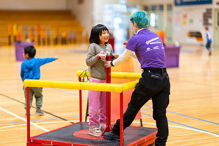 Child on play equipment with helping adult