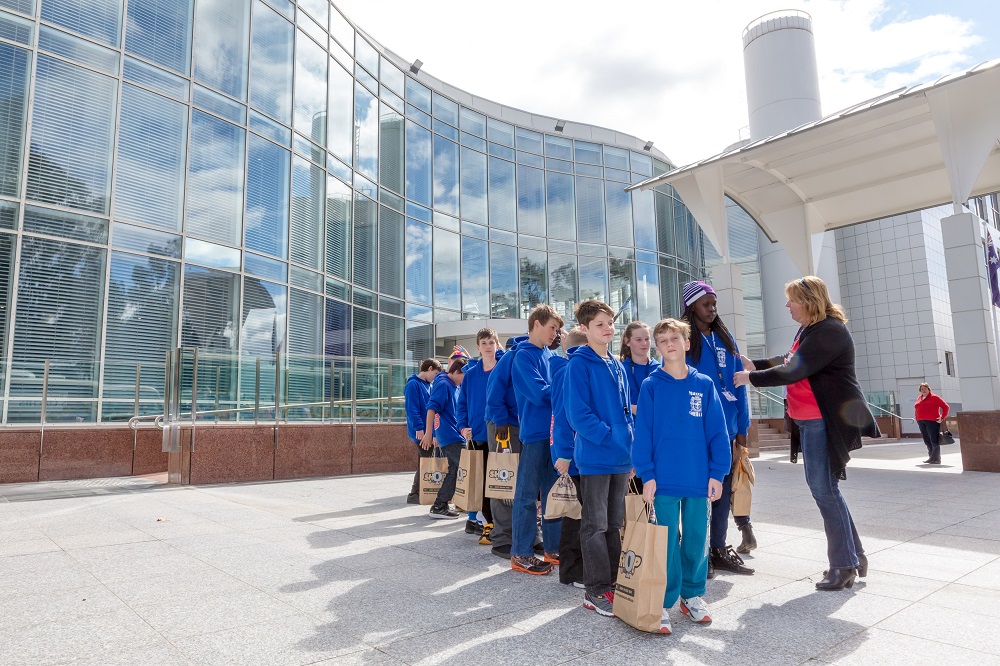 A group of students in uniform lining up outside Questacon