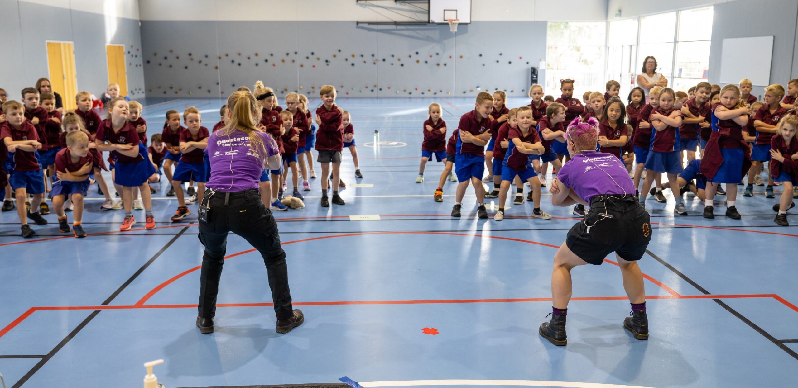 Two young science educators performing in front of an excited group of children