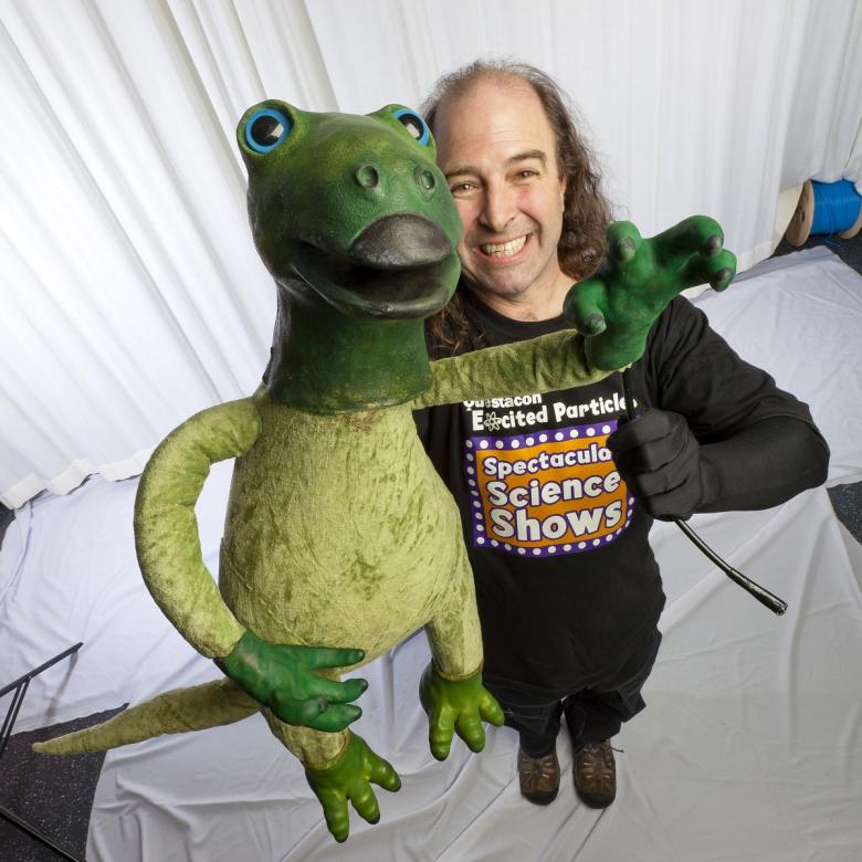 An Excited Particles performer with a dinosaur puppet