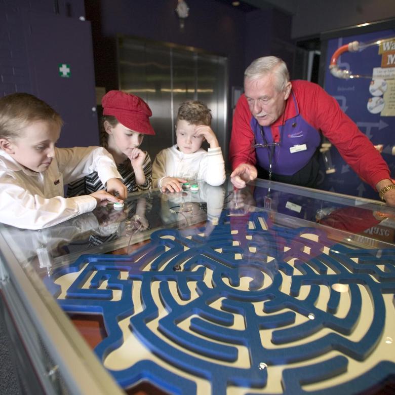 Children operate a pneumatic maze while a Questacon staff member watches