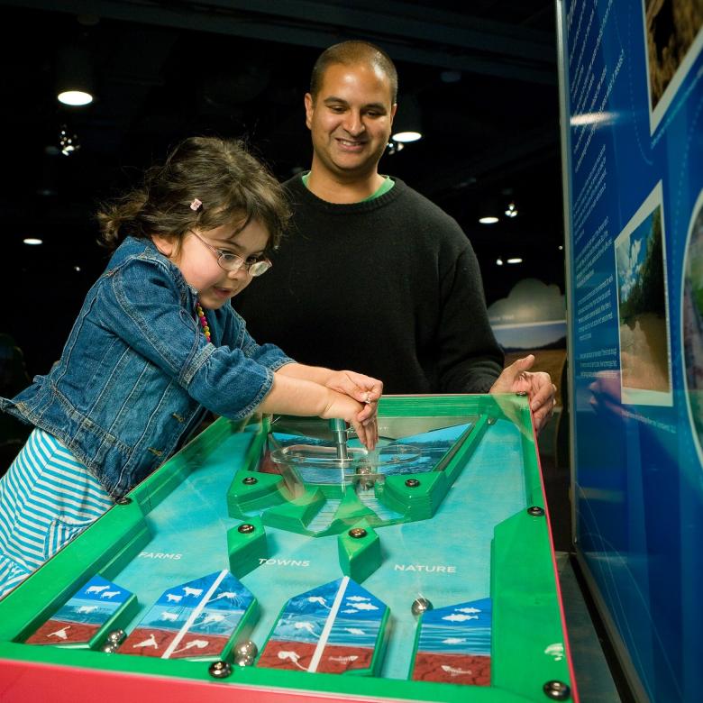 A parent and child operate an exhibit about water