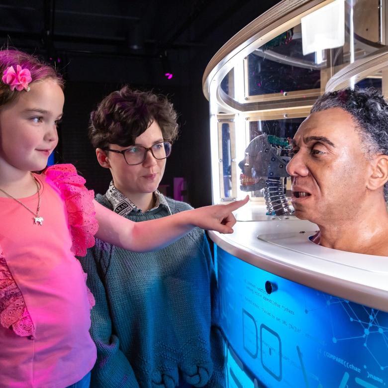 Two children look at a animatronic head