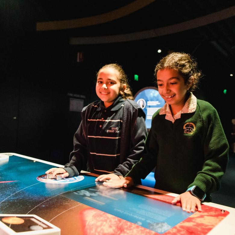 Two children stand by a space-related exhibit