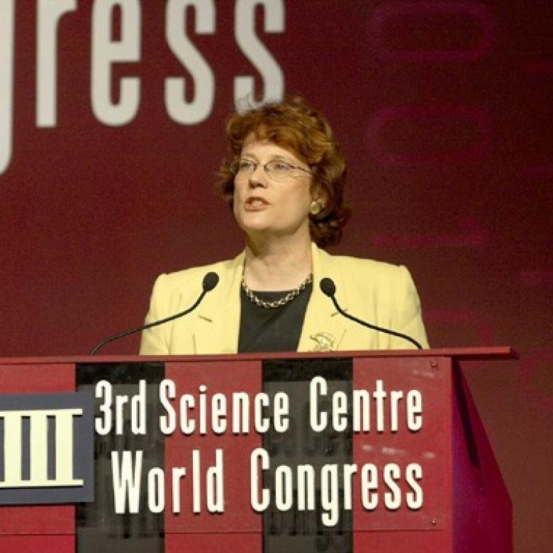 Annie speaks at a podium which reads, "third science centre world congress".