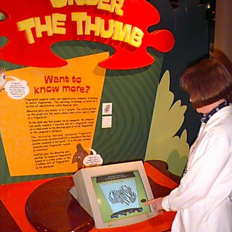 A woman uses a touch-screen nineties computer displaying a close-up image of a fingerprint..