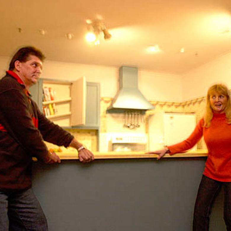 Man and woman hold onto kitchen counter during earthquake simulation