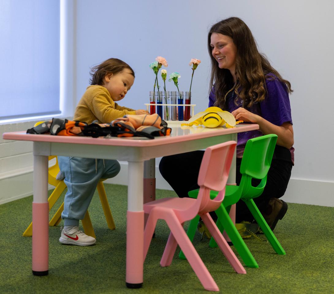 Questacon presenter is chatting to a small child as they sit at an activity table